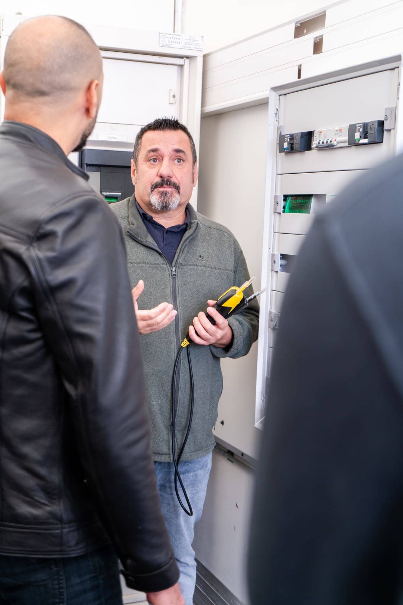 Formateur expliquant les règles de sécurité électrique, appareil de mesure en main